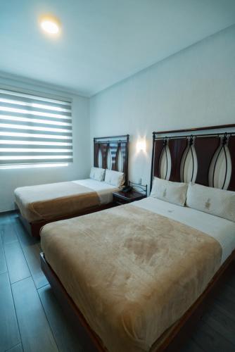 two beds in a hotel room with two bedsvisor at Hotel Alcazar - Guadalajara Centro Historico in Guadalajara
