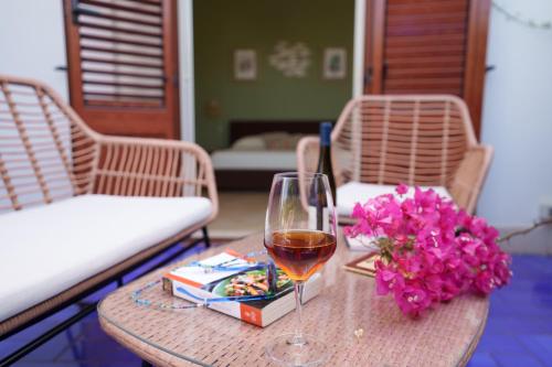 a table with a glass of wine and flowers on it at Le Vele Mondello, villa a due passi dal mare in Mondello