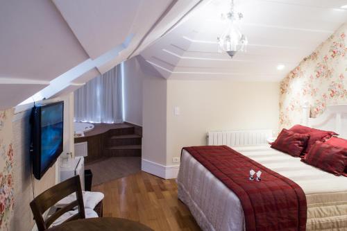 a bedroom with a bed with a red blanket and a tv at Carballo Hotel & Spa in Campos do Jordão
