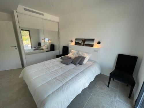 - une chambre avec un lit blanc et une chaise noire dans l'établissement Villa de standing, à Calvi