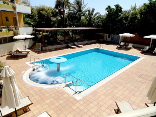 a swimming pool in a resort with chairs and umbrellas at Sitia Bay in Sitia