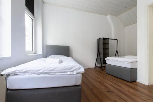 two beds in a room with white walls and wood floors at Gemütliche Unterkunft direkt im Zentrum - 10 min zum Airport Weeze in Kevelaer