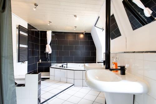 two sinks and a tub in a bathroom with black tiles at Gemütliche Unterkunft direkt im Zentrum - 10 min zum Airport Weeze in Kevelaer