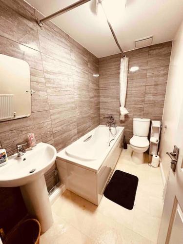 y baño con bañera, aseo y lavamanos. en 5 STAR LUXURY BIG HOUSE, JACUZZI SPA HOT TUB, PARKING, LIVERPOOL CITY CENTRE, SLEEPS 10, EASY LOCK BoX ENTRY! 1 MINUTE DRIVE FROM CITY CENTRE en Liverpool