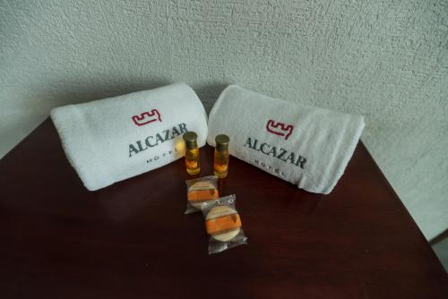 two towels and two bottles of alcohol on a table at Hotel Alcazar - Guadalajara Centro Historico in Guadalajara