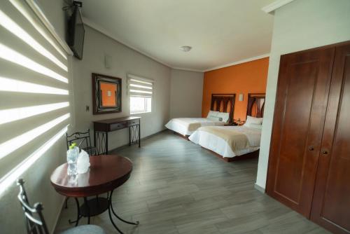 a bedroom with two beds and a table in a room at Hotel Alcazar - Guadalajara Centro Historico in Guadalajara