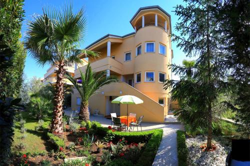 a large yellow building with palm trees in front of it at Villa Jelena in Zadar