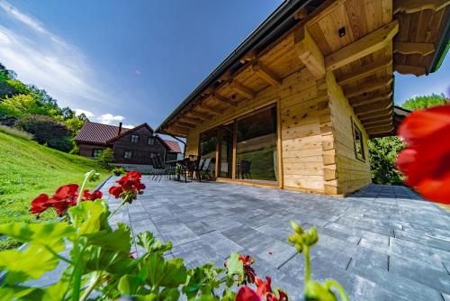 a wooden house with a patio with red flowers at Domek w Górach in Piwniczna-Zdroj