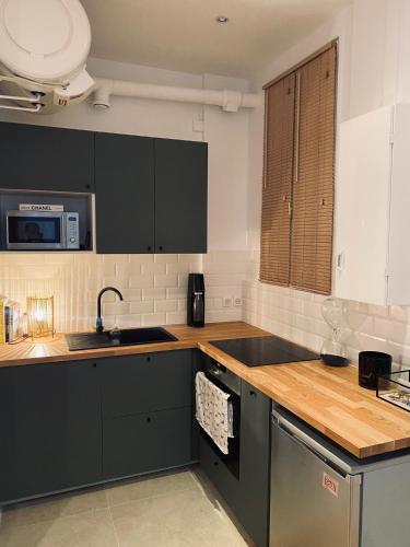 - une cuisine avec des placards noirs et un évier dans l'établissement Appartement rue de Javel, à Paris