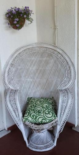 a white wicker chair with a green pillow in it at Casa Vacanze Gio&le in Domusnovas