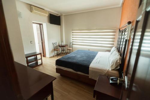 a hotel room with a bed and a table and chairs at Hotel Alcazar - Guadalajara Centro Historico in Guadalajara