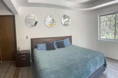 - une chambre avec un lit et 3 miroirs sur le mur dans l'établissement Casa helenico, à Mexico