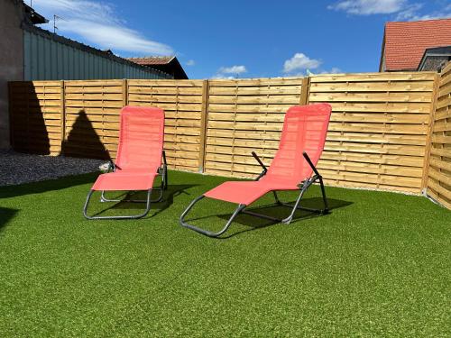 two chairs sitting on the grass in front of a fence at l'Aphrodite in Huttenheim