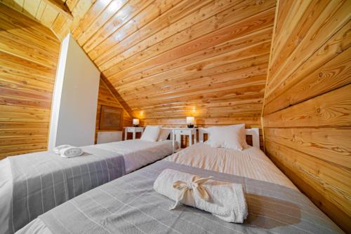 two beds in a room with a wooden ceiling at Domek w Górach in Piwniczna-Zdroj