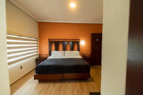 a bedroom with a bed with an orange wall at Hotel Alcazar - Guadalajara Centro Historico in Guadalajara