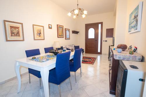 un soggiorno con tavolo bianco e sedie blu di Corallo holiday house Acitrezza ad Acitrezza