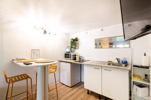 une cuisine avec des armoires blanches et une table et des chaises dans l'établissement Studio charmant & champêtre, à Auch