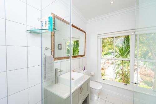 ein weißes Badezimmer mit Waschbecken und Fenster in der Unterkunft Greenhill Farm Parklands Cottage - 2 bedroom 4 guests - Private House in Plettenberg Bay