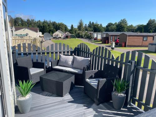 a patio with wicker chairs and a bench and a fence at Freedom Lodge - Aviemore with FREE Starlink Superfast broadband 150mbps - Pet Free in Aviemore