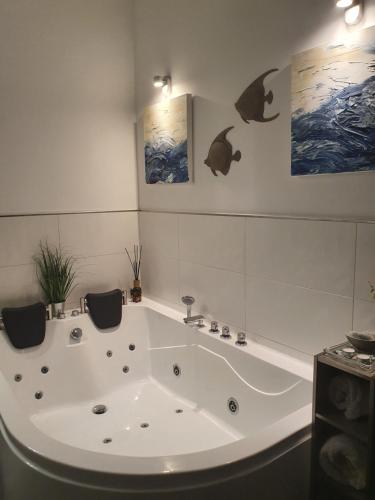 a bath tub in a bathroom with paintings on the wall at Wellness-Pearl Bremerhaven in Bremerhaven