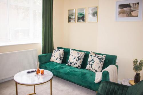 un sofá verde en una sala de estar con mesa en 3 beds - Spacious garden en Streatham Vale