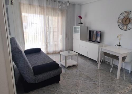 ein Wohnzimmer mit einem Stuhl, einem TV und einem Tisch in der Unterkunft Acogedor apartamento en Daimús junto a la playa con parking privado y piscinas comunitarias in Daimús