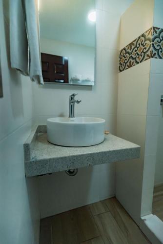 a bathroom with a white sink and a mirror at Hotel Alcazar - Guadalajara Centro Historico in Guadalajara
