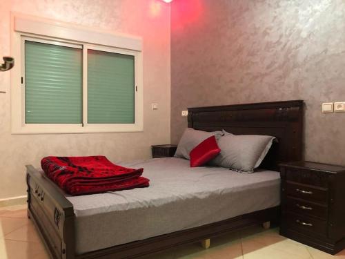 a bedroom with a bed with a red blanket on it at Appartement avec piscine proche de Sidi Bouzid in El Jadida