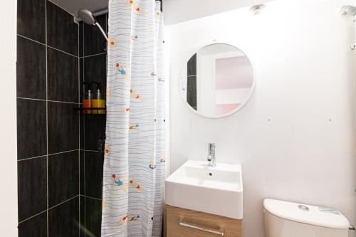 a bathroom with a sink and a shower curtain with birds on it at La vie en rose - appartement cosy - centre ville in Auch