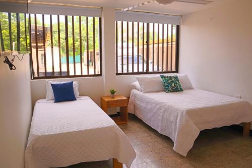 two beds in a room with two windows at Hermoso Apartamento Frente al Mar 2 Habitaciones C13B in Coveñitas