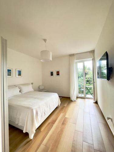 a white bedroom with a bed and a large window at B&B Cellini in Santa Maria di Castellabate