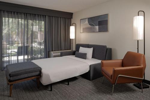 Pokój hotelowy z łóżkiem i krzesłem w obiekcie Courtyard Anaheim Buena Park w mieście Buena Park