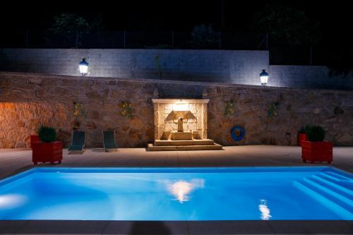 a swimming pool in front of a fireplace at night at Casa do Sabugueiro in Ponte de Lima