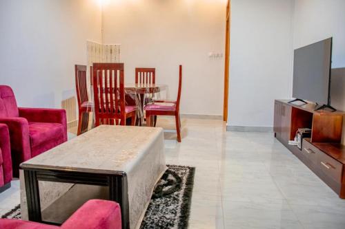 a living room with a table and chairs and a tv at B I G Residence Hotel in Bujumbura