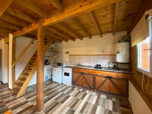 una cocina con techos de madera y una escalera en una casa en Cabaña Bigua en San Martín de los Andes