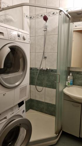 y baño con ducha y lavadora. en Cozy budget room w/ balcony in shared apartment, en Vantaa