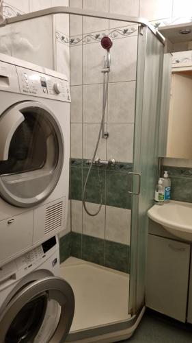 a shower in a bathroom with a washing machine at Cozy budget room w/ balcony in shared apartment in Vantaa