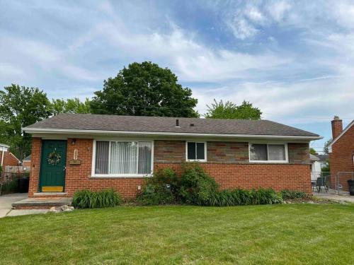 a brick house with a green door on a yard at Cozy Bungalow in Madison Heights in Madison Heights