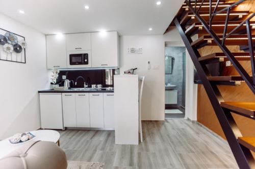 a kitchen with white cabinets and a spiral staircase at Aria in Cetinje