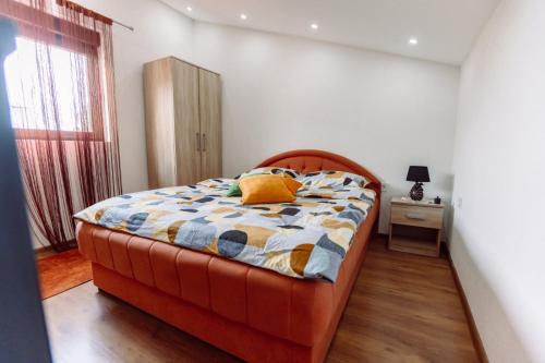 an orange bed in a white room with a window at Aria in Cetinje