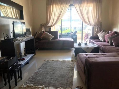 - un salon avec un canapé, une table et une télévision dans l'établissement Bel Appartement pour vacances, à Sidi Rahal