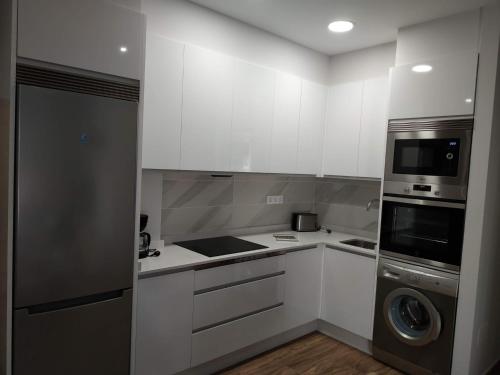 a kitchen with white cabinets and a washer and dryer at O SEGREDO DA CORUXA in Vilariño