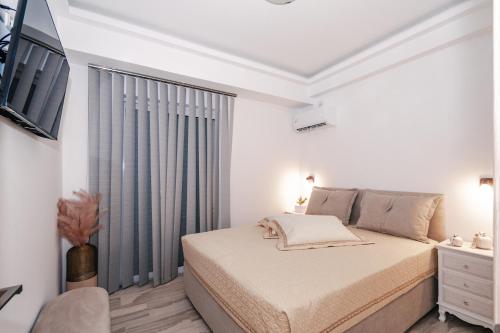 a white bedroom with a bed and a window at Chistina’s brand new apartment in Kyparissia