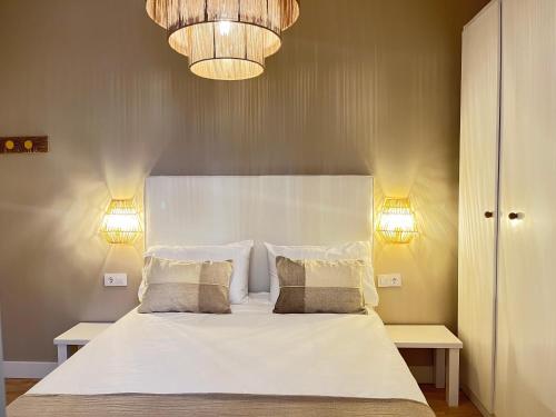 1 dormitorio con 1 cama blanca grande y 2 luces en COQUETO APARTAMENTO, en Torrelavega