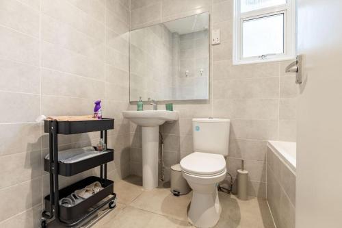 a bathroom with a white toilet and a sink at Cozy 3-Bedroom Flat in Willesden Green London in London