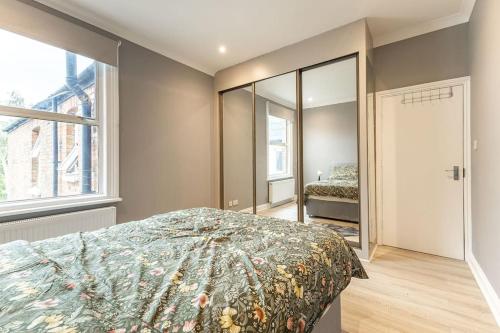 a bedroom with a bed and a large window at Cozy 3-Bedroom Flat in Willesden Green London in London