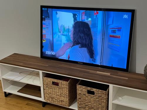 una TV a schermo piatto seduta sopra un centro di intrattenimento di Appartement F2 a Longjumeau