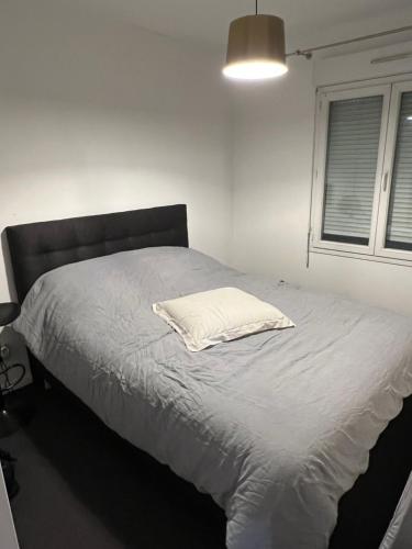 un letto con un cuscino bianco in una camera da letto di Appartement F2 a Longjumeau