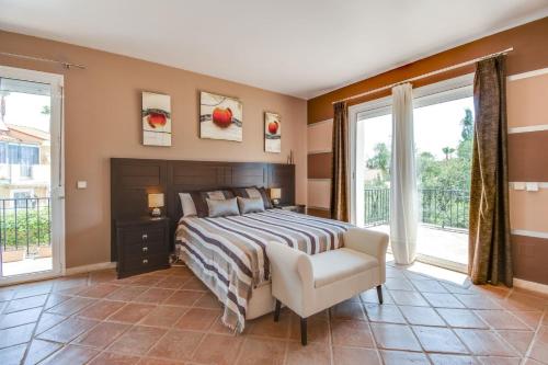 um quarto com uma cama, uma cadeira e janelas em Villa Duquesa em Manilva