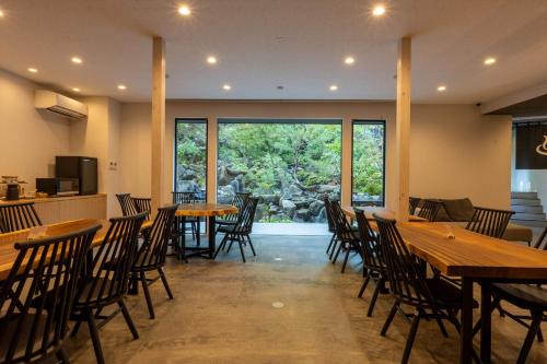 上田的住宿－Bessho Onsen Midoriya，餐厅设有木桌、椅子和大窗户。